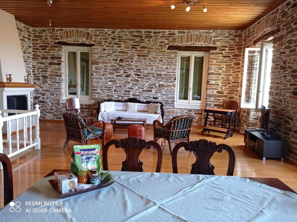 een woonkamer met een tafel en stoelen en een bakstenen muur bij Marina Traditional Stonehouse in Afétai