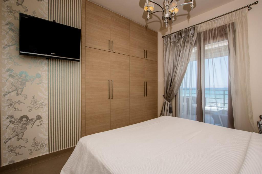 a bedroom with a bed and a flat screen tv at White Crystal Beachfront Apartment in Gournes