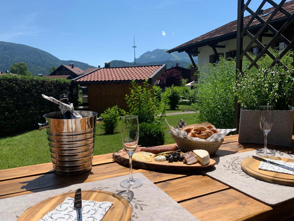 een houten tafel met eten en wijnglazen erop bij Ferienwohnung Sonnenplatzl in Reit im Winkl