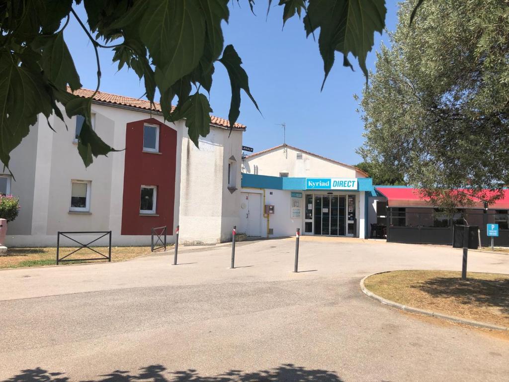 un bâtiment avec une rue en face dans l'établissement Kyriad Direct Perpignan - Aeroport, à Rivesaltes