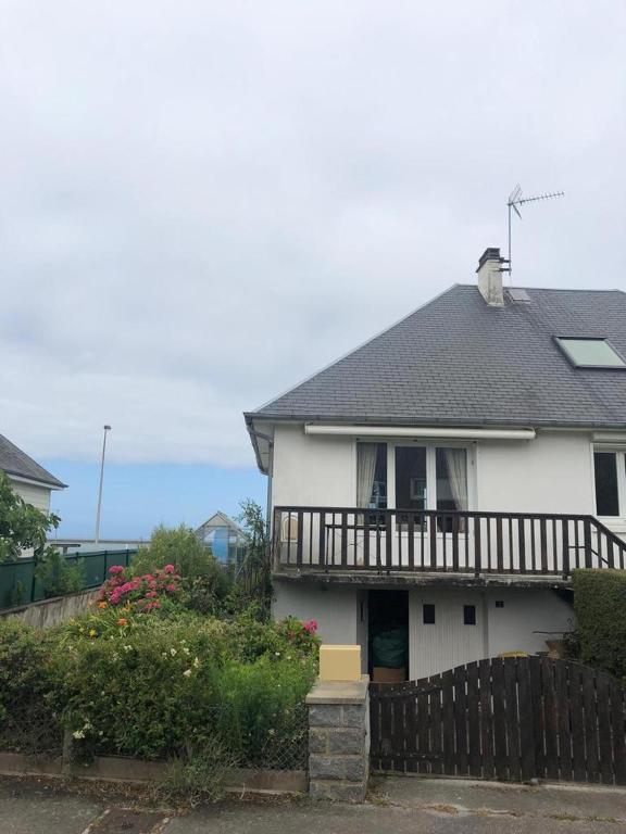 une maison blanche avec un balcon au-dessus dans l'établissement Grande maison vue sur mer, à Équeurdreville-Hainneville
