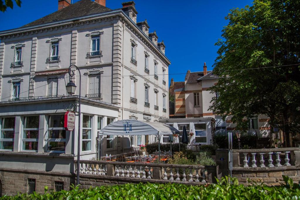 - un bâtiment blanc avec un parasol devant dans l'établissement Hôtel des Thermes, à Bourbon-lʼArchambault