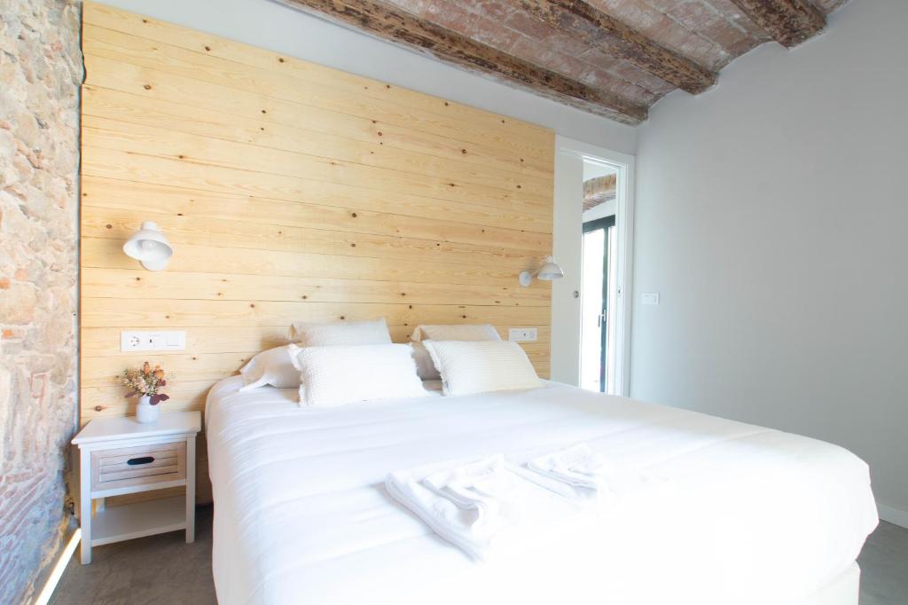 1 dormitorio con cama blanca y pared de madera en Bruma Boutique Apartment, en Girona