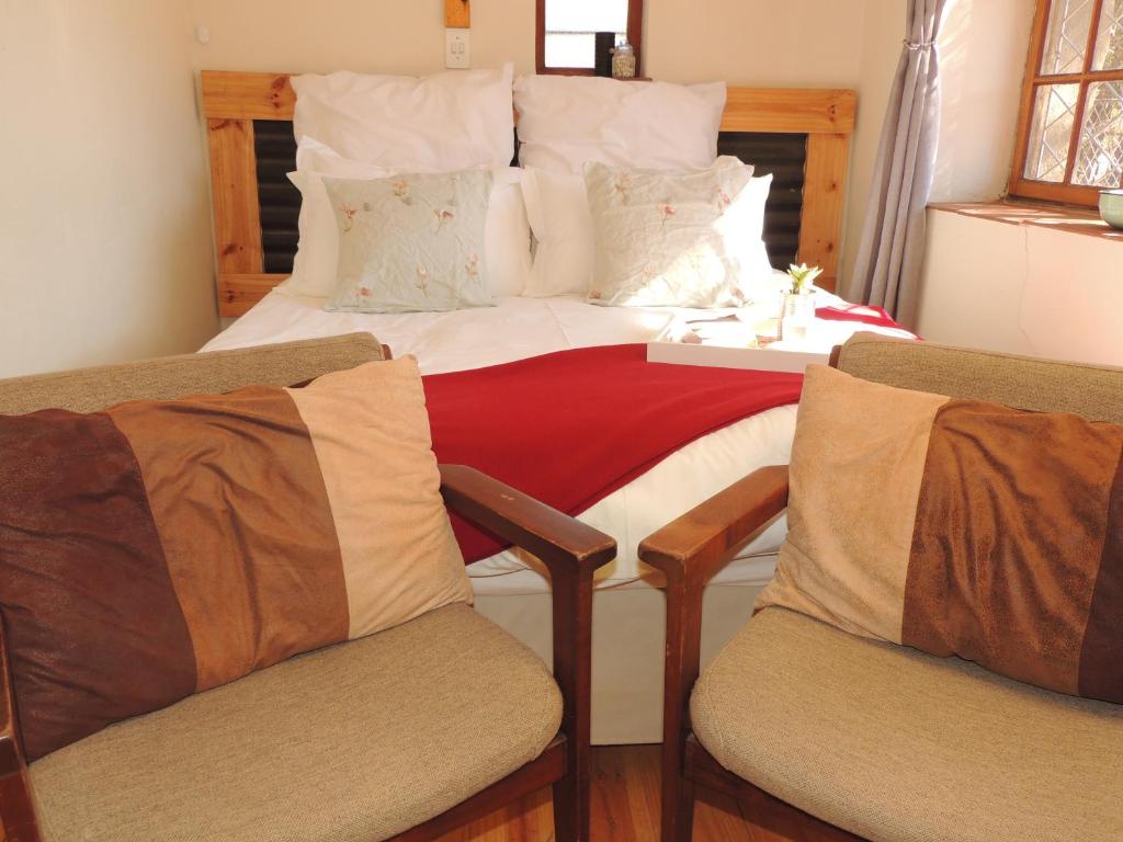 a bedroom with a bed with two chairs in it at Stone Haven at Nieu Bethesda in Nieu-Bethesda