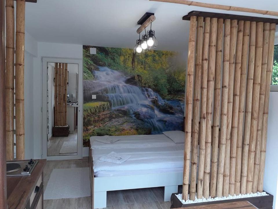 łóżko w pokoju z obrazem wodospadu w obiekcie Casa Bambus Sovata 2 w mieście Sovata