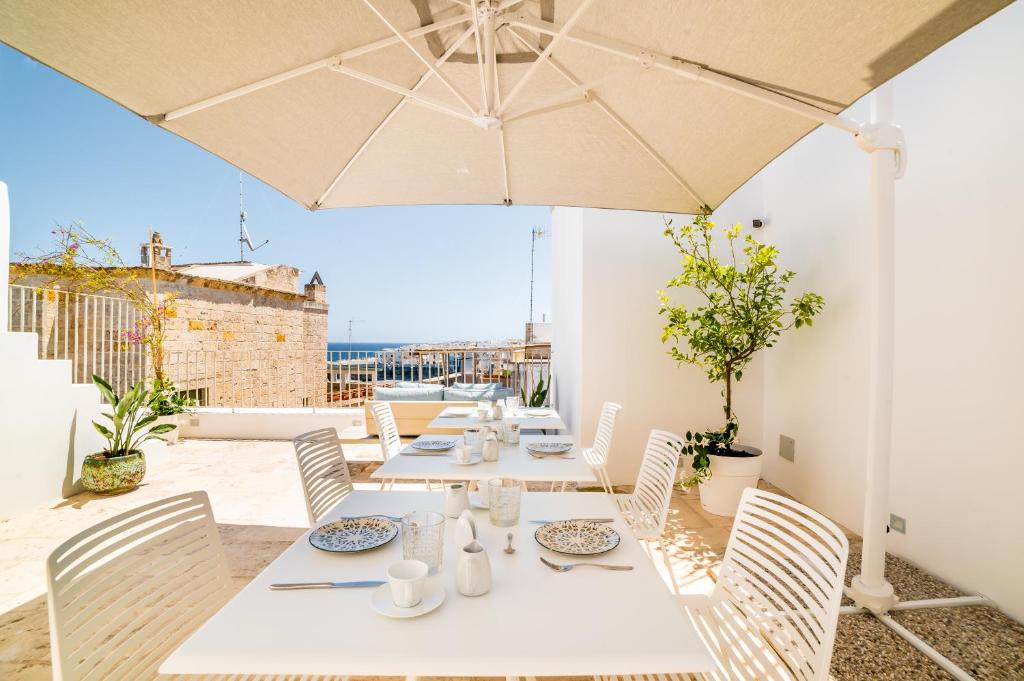 a table with chairs and an umbrella on a patio at Tre Archi Suite & Relais in Polignano a Mare
