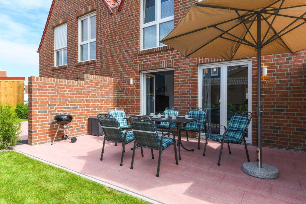 a patio with a table and chairs and an umbrella at Ferienhaus Ella in Dornumersiel