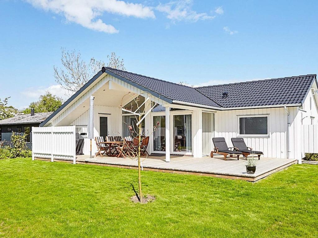 a white house with a deck and chairs in a yard at 6 person holiday home in Slagelse in Slagelse