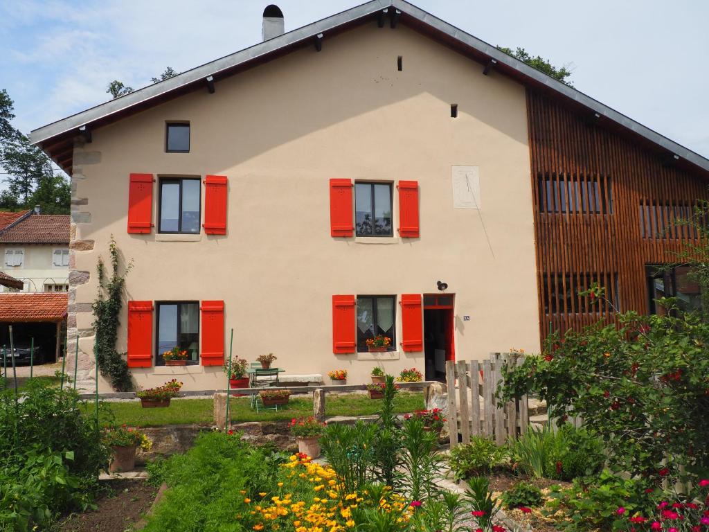 une maison avec des volets rouges et un jardin dans l'établissement Chambres d'hôtes du Ruisseau d'Argent, à Archettes