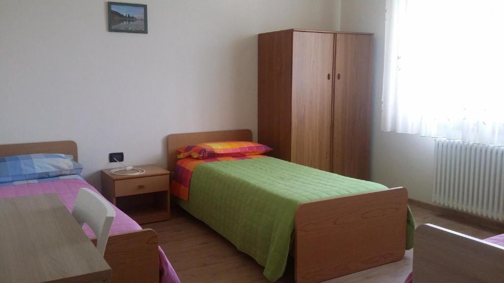 a bedroom with two beds and a wooden cabinet at Casa Ferrari Michela in Calceranica al Lago