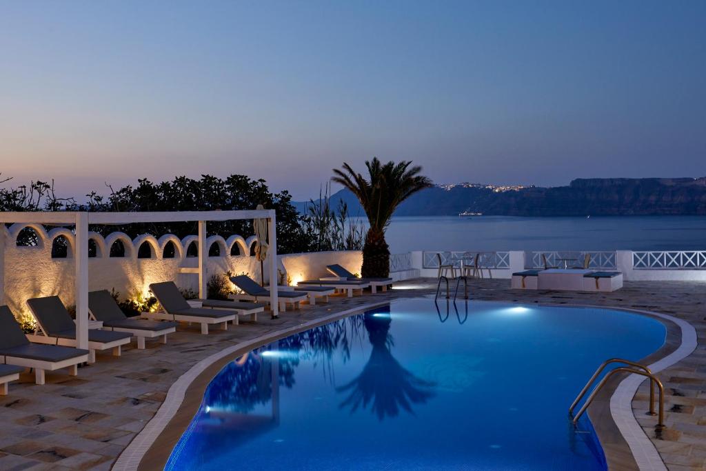 a pool with lounge chairs and a view of the water at Santorini View in Akrotiri