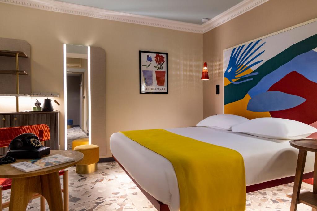 a bedroom with a large bed with a large painting on the wall at Hôtel De La Paix in Paris