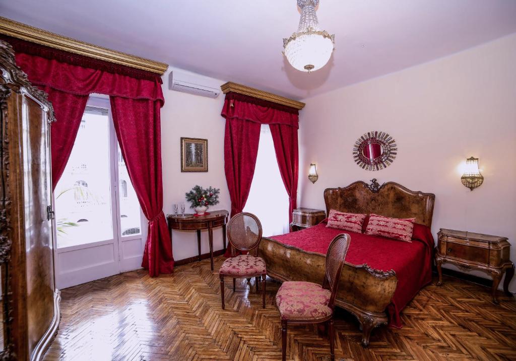Schlafzimmer mit einem Bett mit roter Bettwäsche und roten Vorhängen in der Unterkunft WELL COME - Palazzo Reale in Neapel