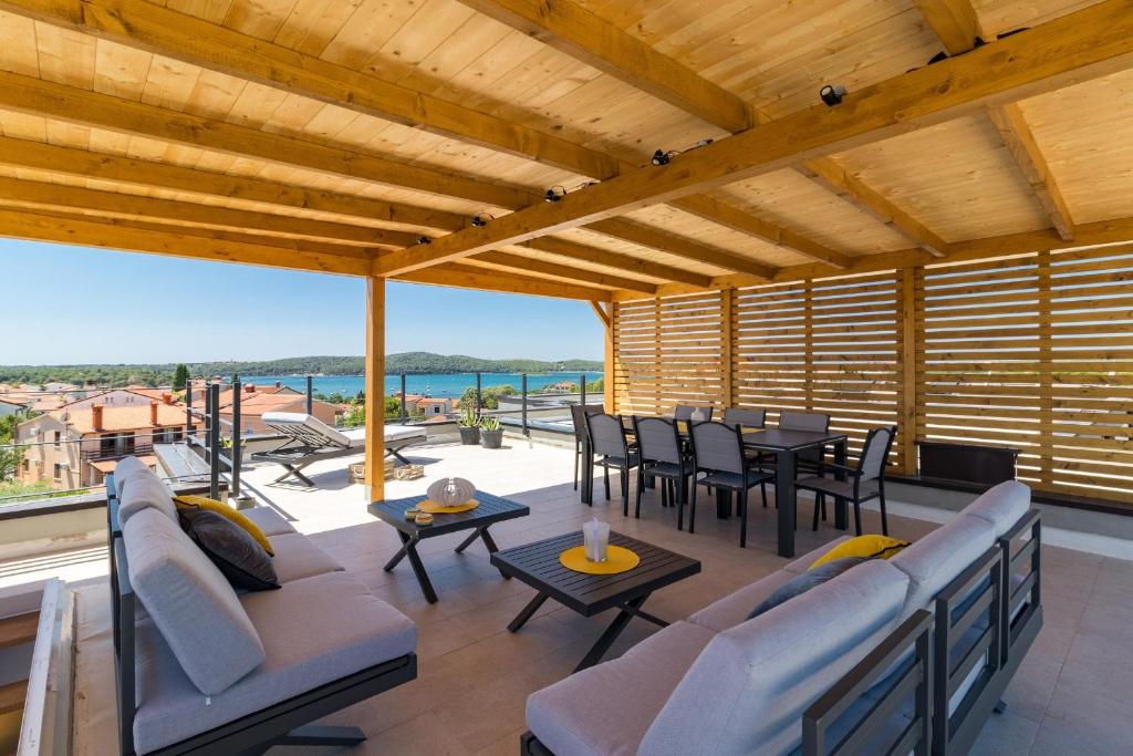 d'une terrasse avec des chaises et des tables et une vue sur l'océan. dans l'établissement Penthouse Apartment Sax, à Medulin