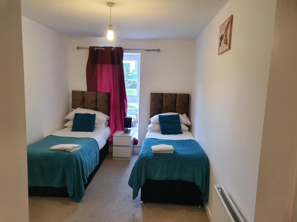 two beds in a room with a window at Vetrelax Basildon Blake Apartment in Basildon