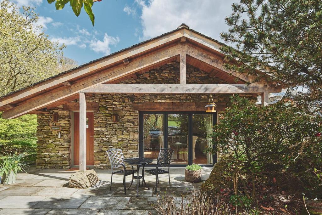 a stone house with a table and chairs on a patio at Twitchers Cottage in Kendal