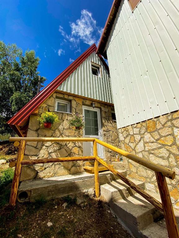 a stone house with a wooden fence in front of it at TARA BUNGALOV in Žabljak