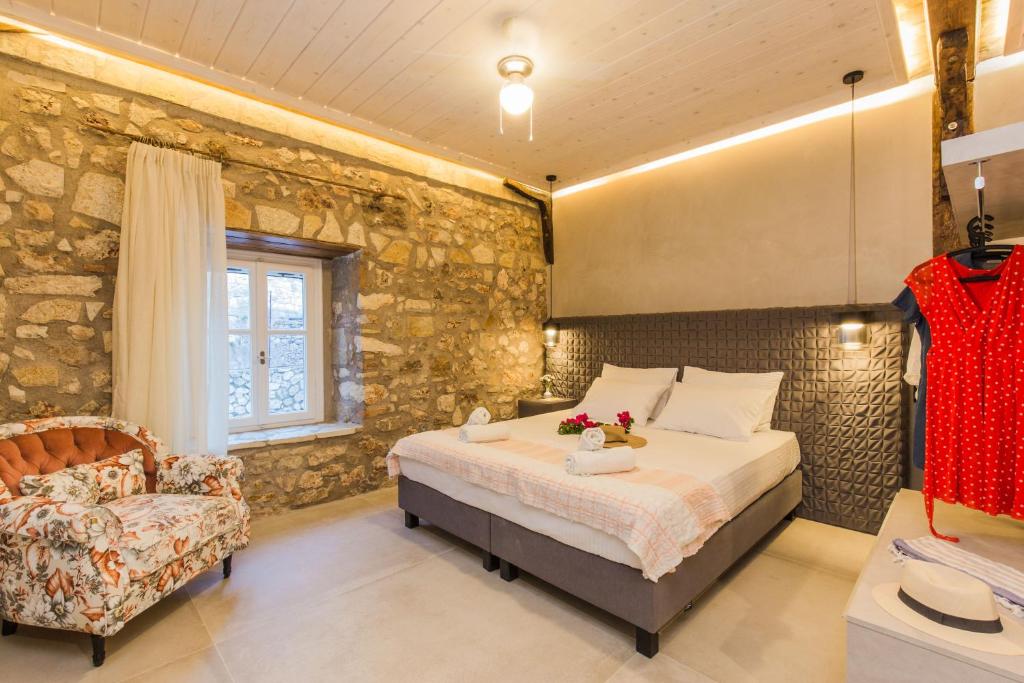 a bedroom with a bed and a chair at Stone Suites at Lefkada's Old Port in Lefkada