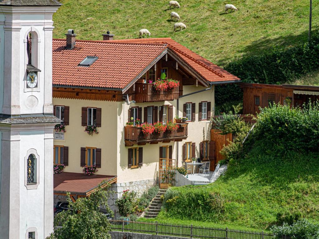 a building with flowers on the balconies and a clock tower at Ferienwohnung Watzmannblick Maria Gern in Berchtesgaden