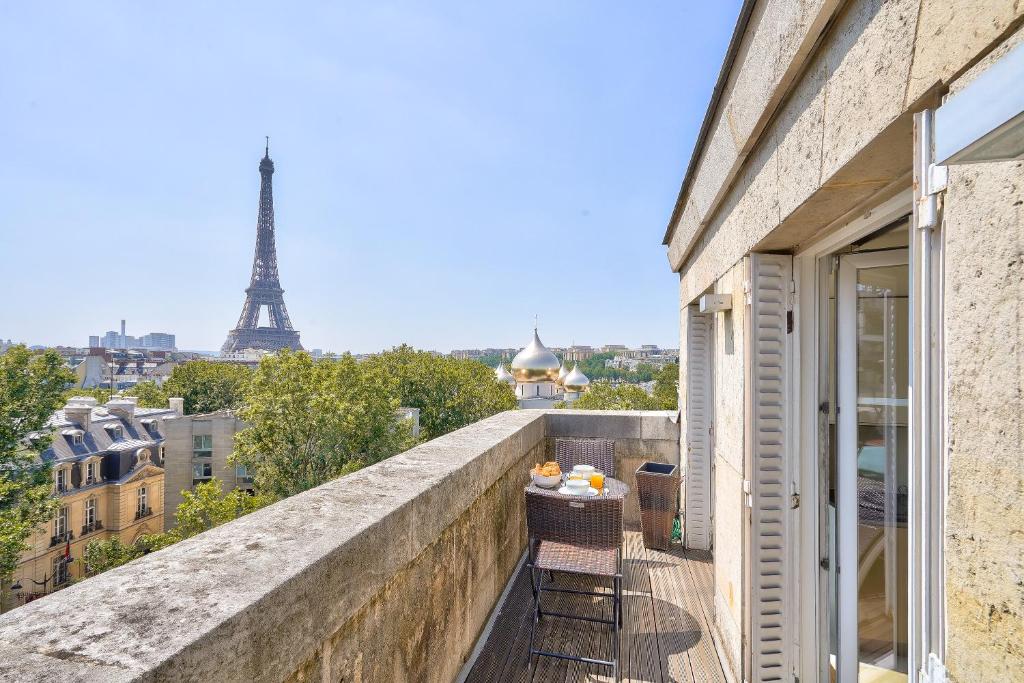 d'un balcon avec une table et des chaises et la tour Eiffel. dans l'établissement Designed Studio with AC-Terrasse Vue Tour Eiffel, à Paris
