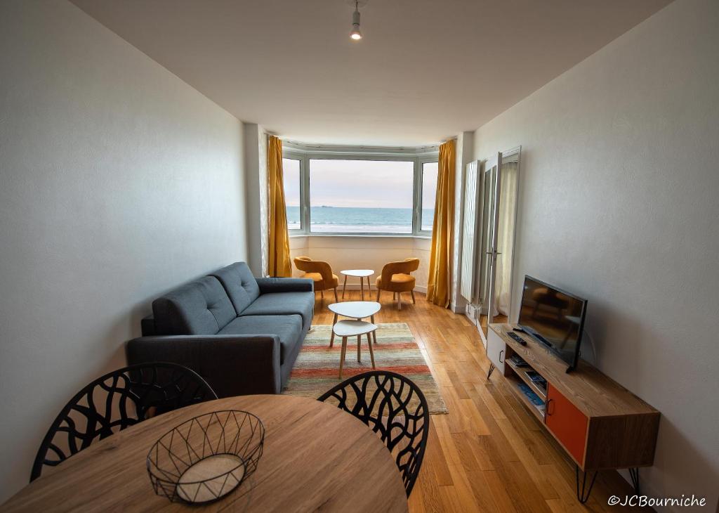 a living room with a couch and a television at APPARTEMENT PLEINE VUE MER 34 Ch. du Sillon Saint-Malo Plage in Saint Malo