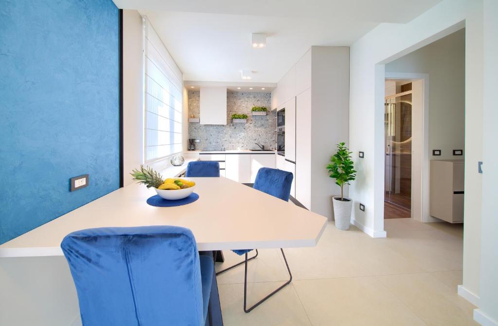 uma cozinha com uma mesa branca e cadeiras azuis em Residence Vrbnik em Vrbnik