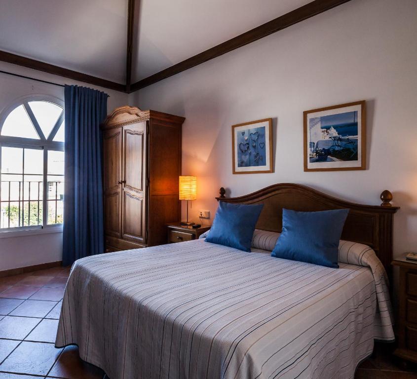 a bedroom with a bed with blue pillows and a window at Hotel El Molino in Osuna