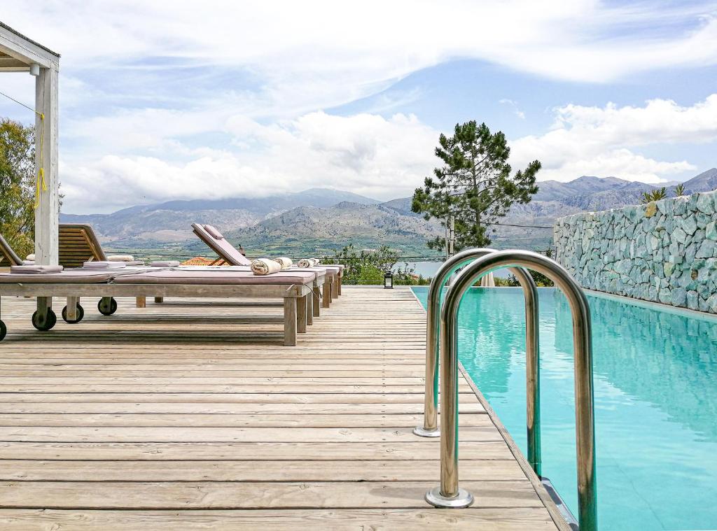 a wooden deck with a swimming pool with mountains in the background at Villa Aetos in Paleros