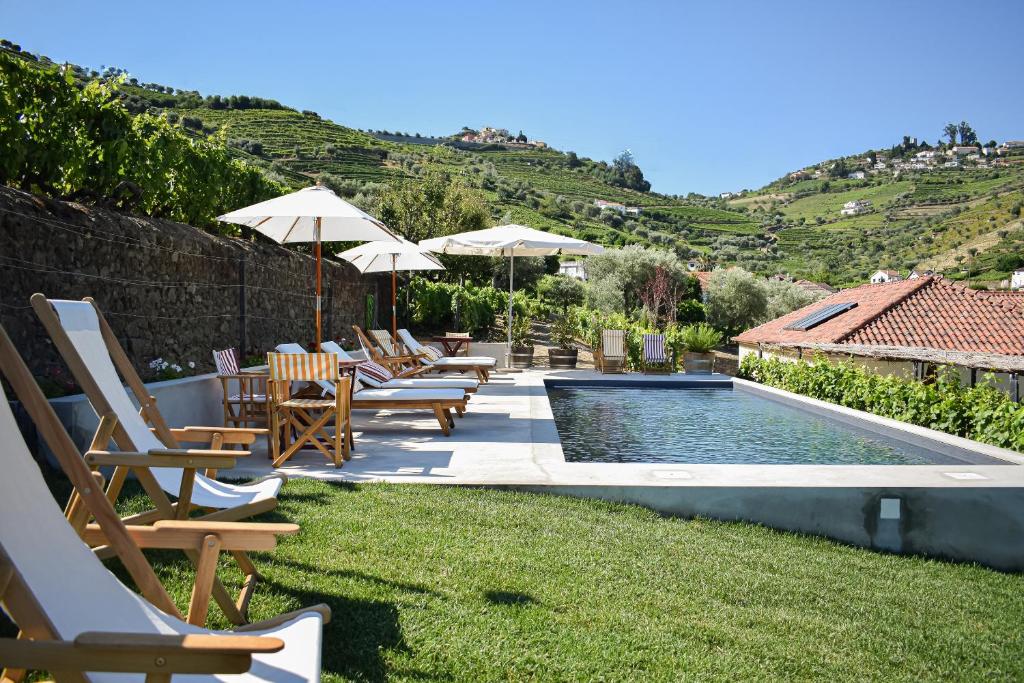 una piscina con sillas y sombrillas en un patio en Quinta da Casa Amarela- Casas da Quinta - Turismo em Espaço Rural, en Lamego