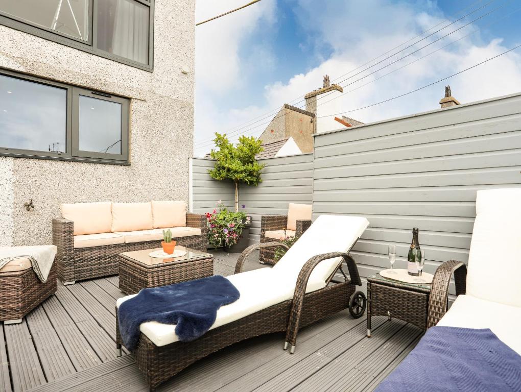 a patio with wicker chairs and a bed and tables at Arlan in Benllech