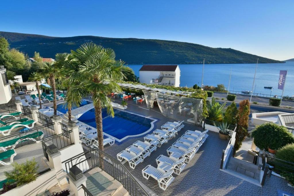 a beach area with a pool, chairs, and tables at Hotel Xanadu in Herceg-Novi
