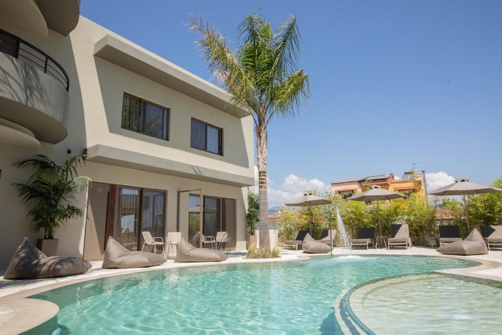 una piscina di fronte a una casa con una palma di Allonda Seafront Experience a Stavros