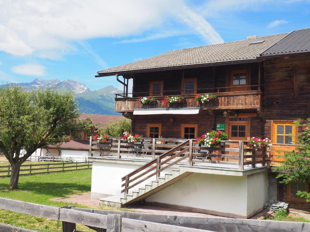 una gran casa de madera con flores en el balcón en Ferienhaus Innerkienzerhof - Urlaub am Bauernhof, en Matrei in Osttirol
