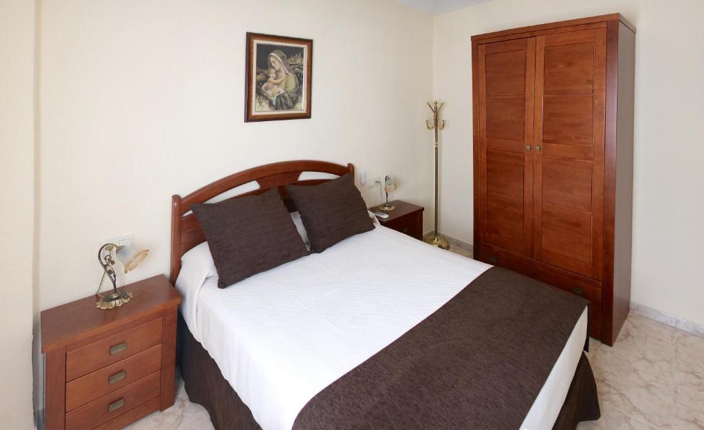 1 dormitorio con 1 cama grande y armario de madera en VIVIENDA TURÍSTICA CARMELITAS DESCALZAS, en Úbeda