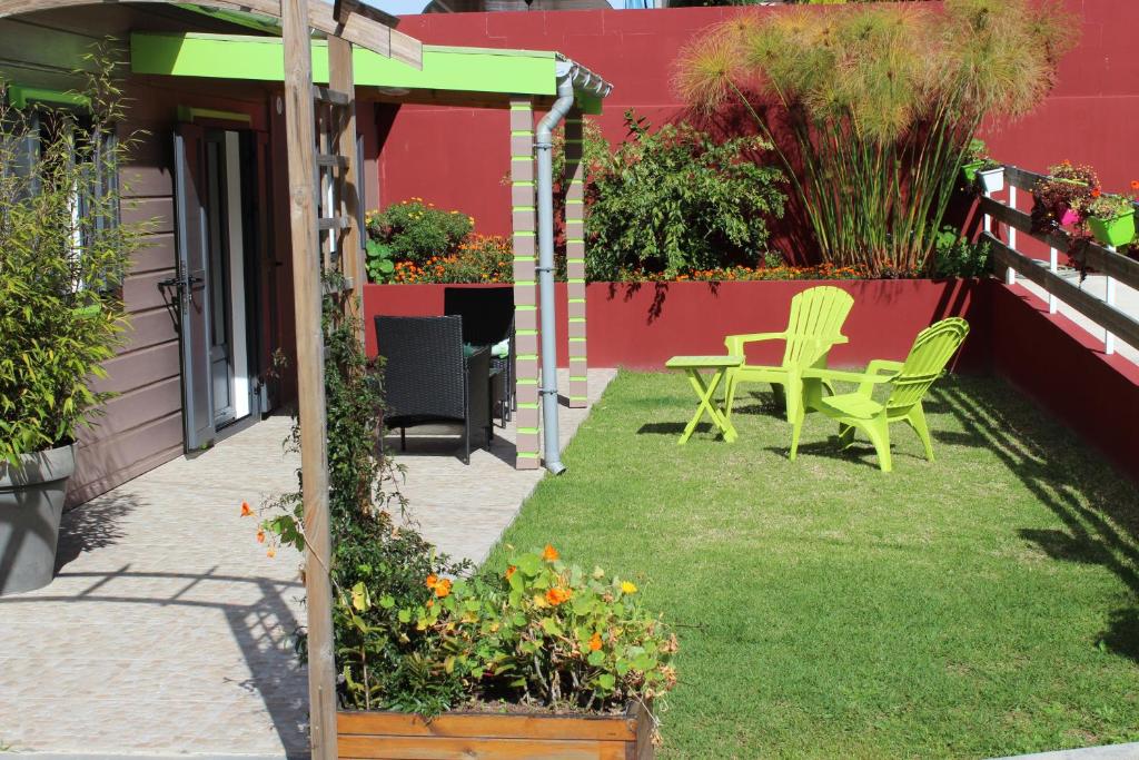 un patio con mesa, sillas y flores en CASAMELIAS Le chalet en Cilaos