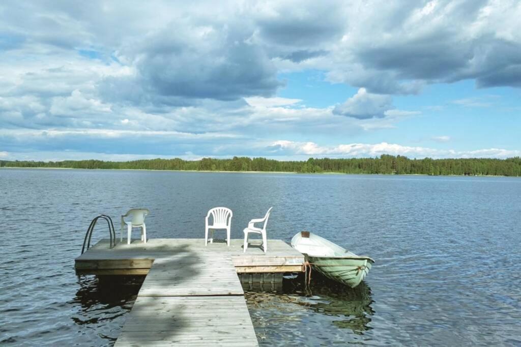 two chairs and a boat on a dock on a lake at Cotteg Marjakallio (BerryRock) in Punkaharju