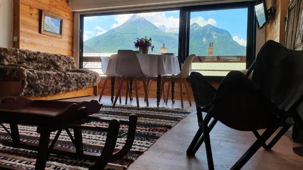 a living room with a table and a large window at Studio chaleureux station de Serre Chevalier 1200 (Briançon) in Briançon