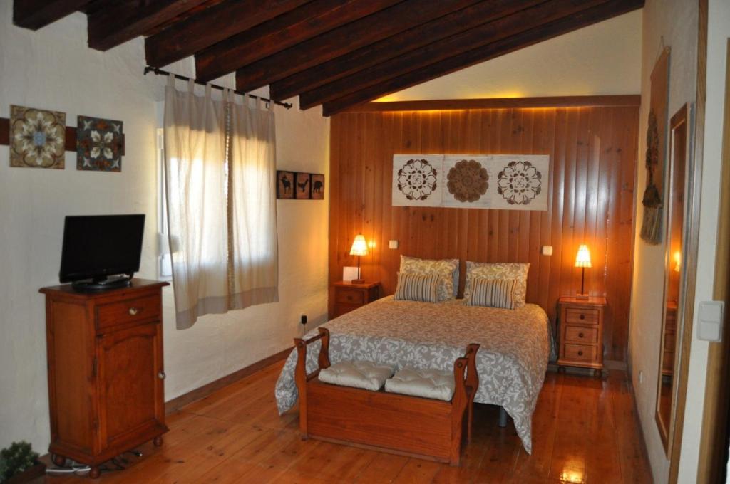 ein Schlafzimmer mit einem Bett und einem Fernseher darin in der Unterkunft El Rincón de Pirón in Losana de Pirón