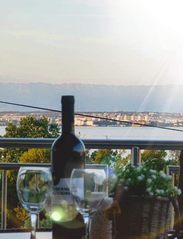 a bottle of wine sitting on a table with two glasses at Apartman Sara in Preko