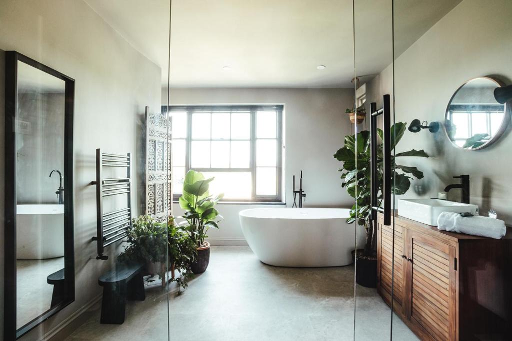 a bathroom with a large tub and plants in it at The fig in Rye