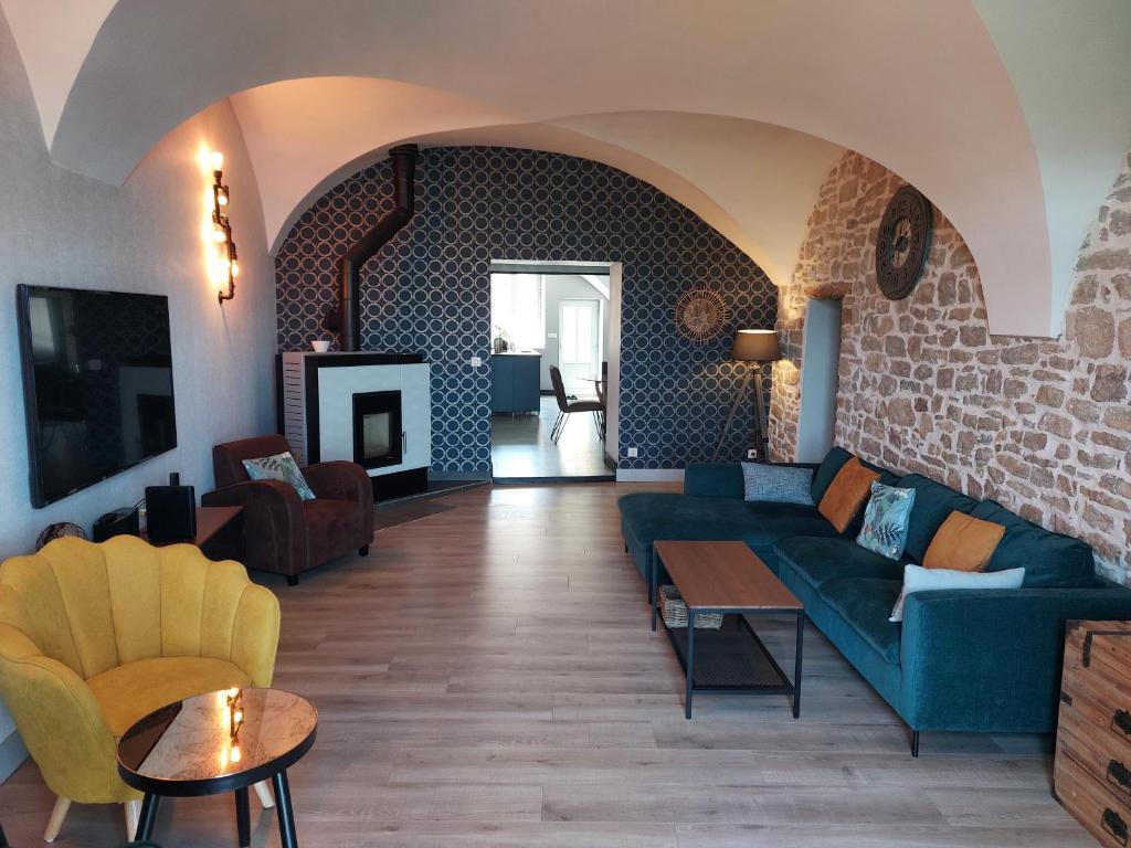 L'INATTENDU Vue imprenable, lits préparés et ménage inclus في Montaigu: غرفة معيشة مع أريكة زرقاء وجدار من الطوب