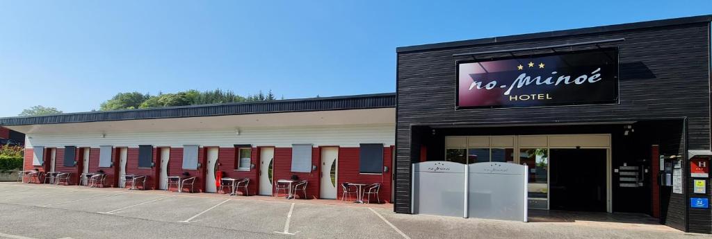 un bâtiment avec des tables et des chaises dans un parking dans l'établissement Hotel No Minoé, à Locminé