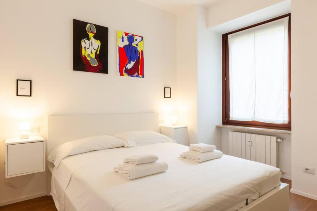 1 dormitorio con 1 cama blanca grande y toallas. en Lazzi - A.C. - Wi-Fi - Flexyrent Apartment en Milán