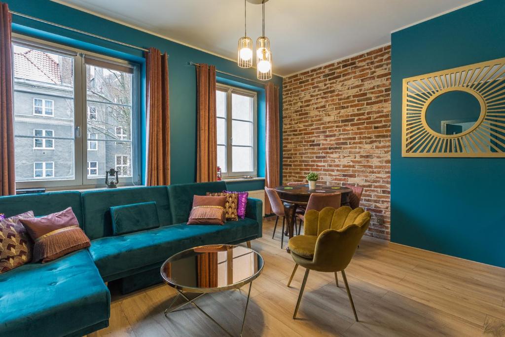 a living room with a blue couch and a brick wall at Apartament Cichy Zakątek obok fontanny Neptuna in Gdańsk