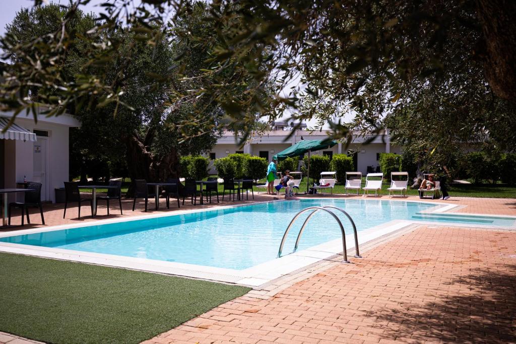 - une piscine avec des chaises et une personne debout à côté dans l'établissement Hotel Eden, à Carovigno