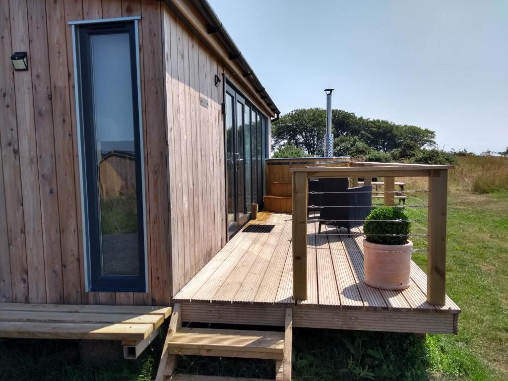 una terraza de madera junto a una casa con una planta en Cleeves Cabins Arran Lodge with hot tub luxury en Dalry