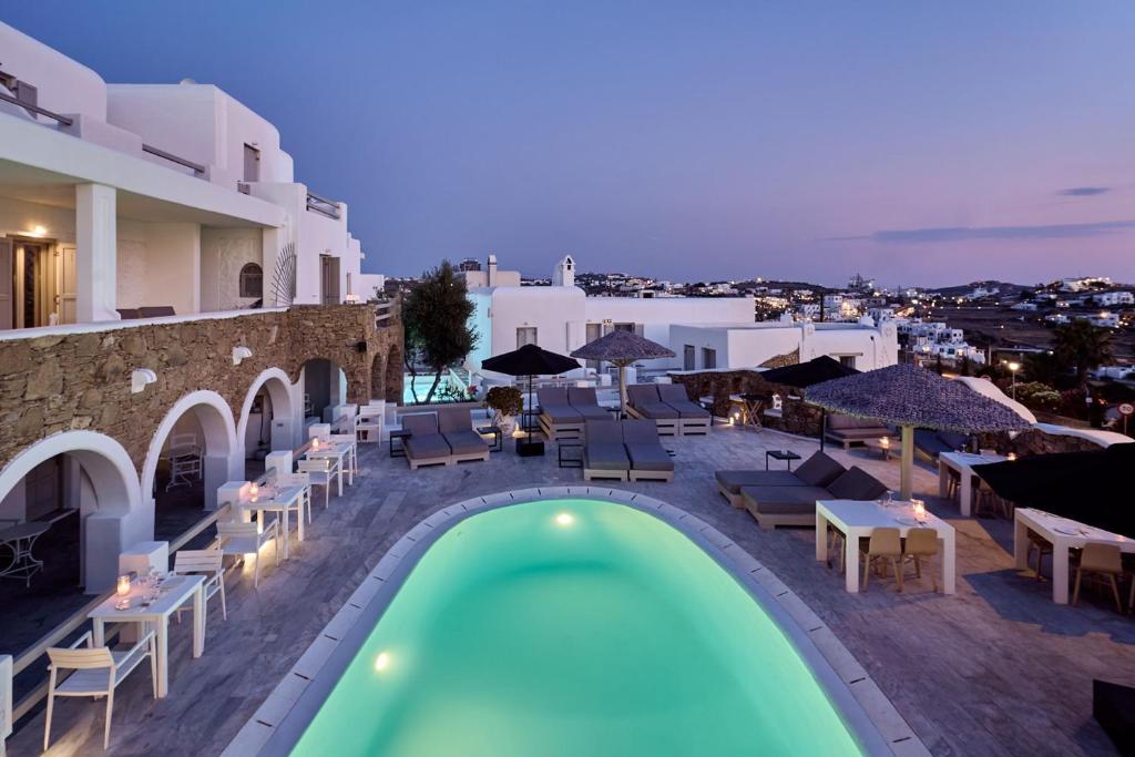 uma vista para uma piscina com cadeiras e guarda-sóis em Paolas Τown Boutique Hotel em Míconos