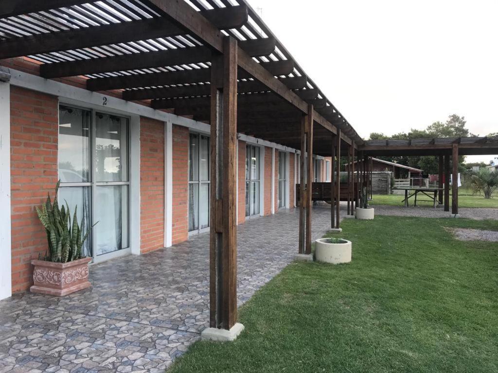 a brick building with a pergola and a patio at Hostal Lo de Mili in Chuy