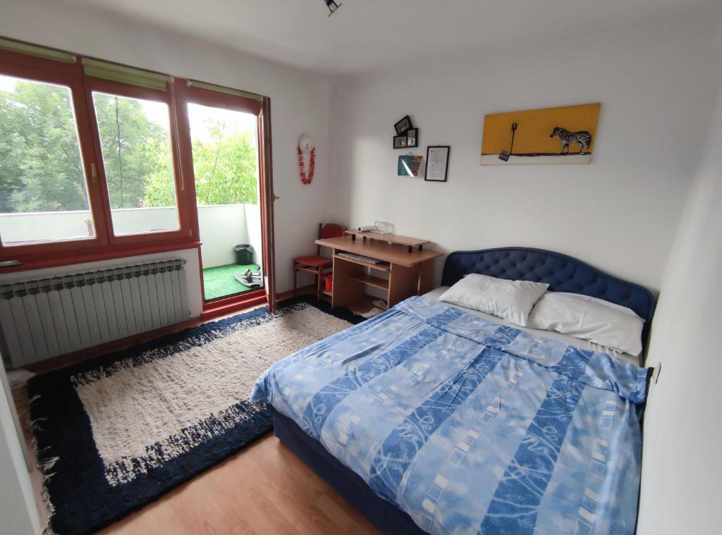 a bedroom with a bed and a desk and a window at Cozy room with a balcony in Sarajevo