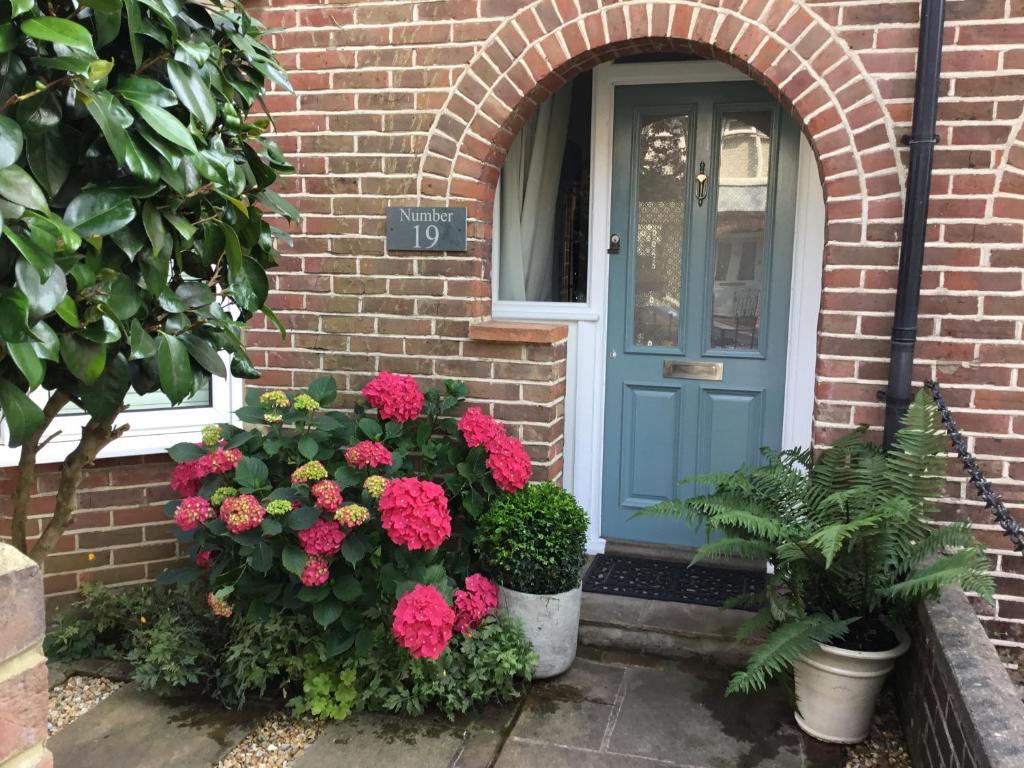 NUMBER 19 Chichester B&B في شيشستر: الباب الأزرق مع الزهور أمام المنزل